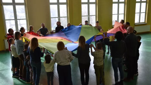 Uczestnicy spotkania w czasie zabawy chustą integracyjną.