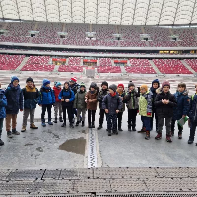 Uczniowie klasy 2D na płycie Stadionu Narodowego pozujący do zdjęcia.