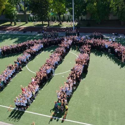 Uczniowie szkół salezjańskich przy ul. Wodnej ustawieni w formie logo domku salezjańskiego na boisku szkolnym.