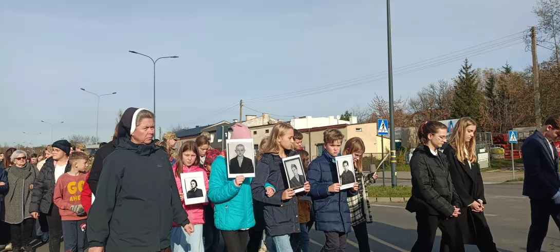 Uczniowie niosący fotografie ofiar