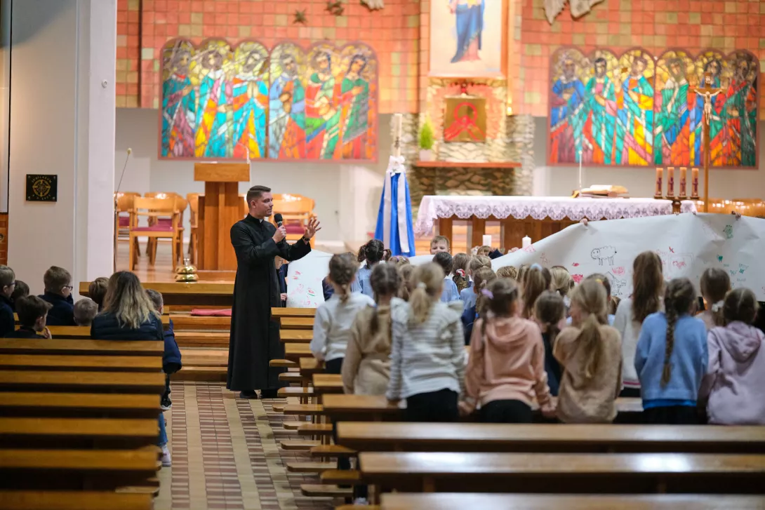 Dzieci wczesnoszkolne prezentują efekt swojej pracy podczas spotkania adwentowego z ks. Łukaszem Dumińskim.