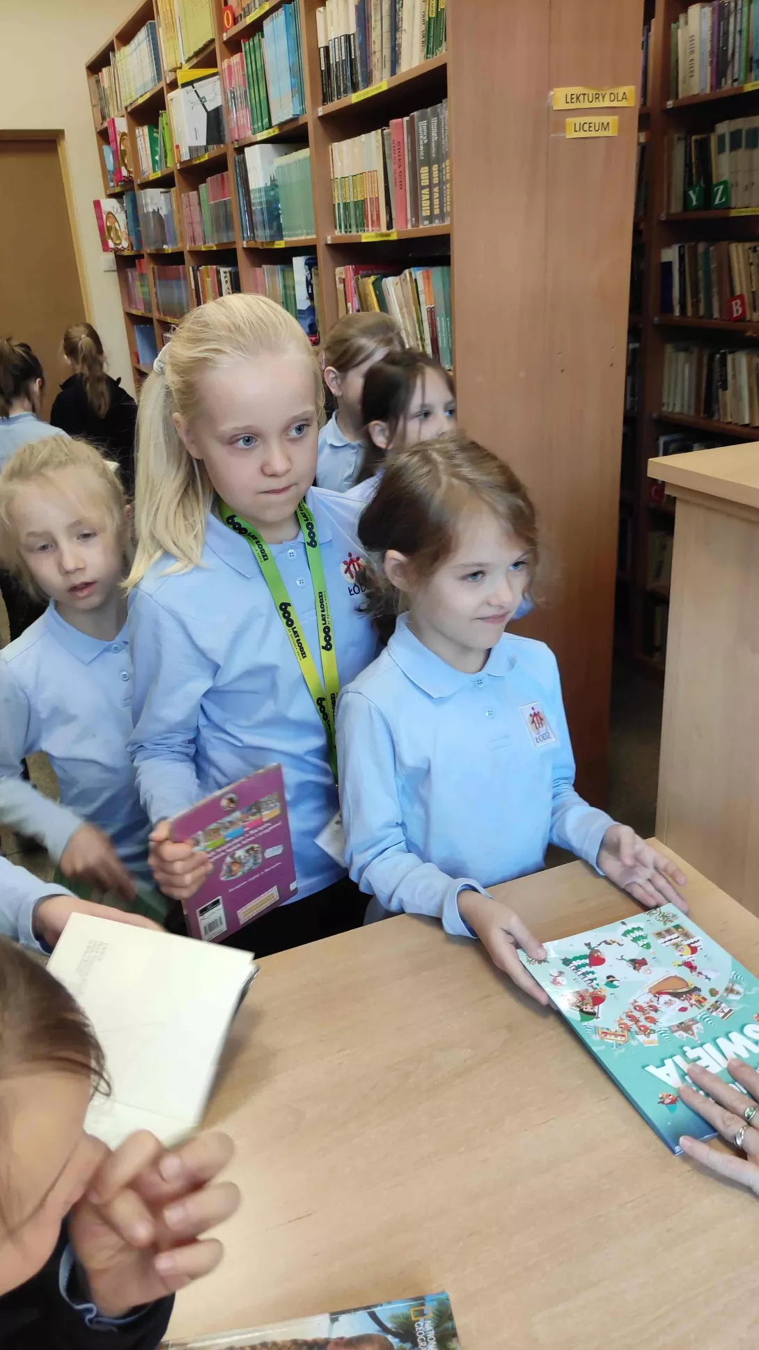 Dziewczynki z klasy 1a wypożyczają swoje pierwsze książki ze szkolnego księgozbioru