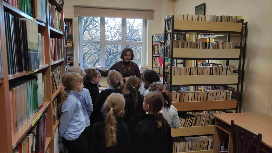 Uczennice klasy 1a SSP słuchają zasad dotyczących korzystania z księgozbioru biblioteki szkolnej omawianych przez nauczyciela bibliotekarza