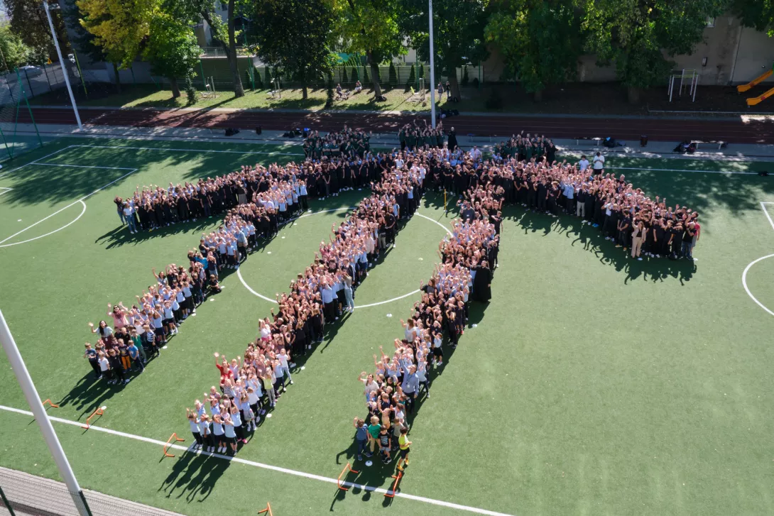 Uczniowie szkół salezjańskich przy ul. Wodnej ustawieni w formie logo domku salezjańskiego na boisku szkolnym.