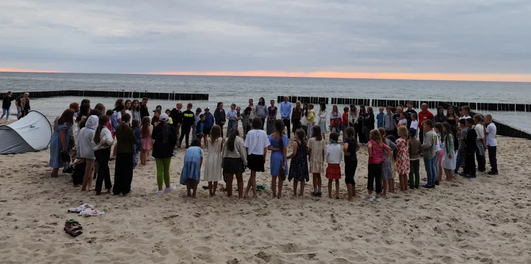 Cała grupa: uczestnicy kolonii i opiekunowie na plaży.