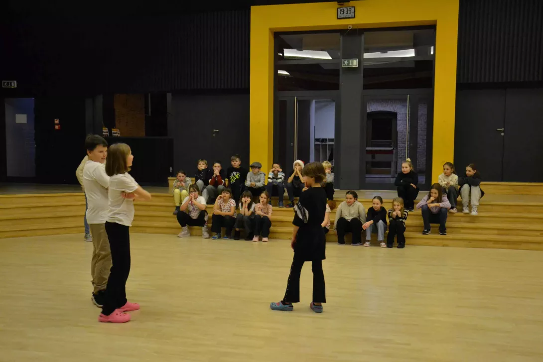 Uczniowie teatru Beznazwy bawią się w improwizację w auli szkolnej.