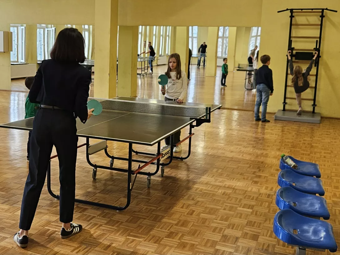 Uczniowie z rodzicami grają w tenisa stołowego