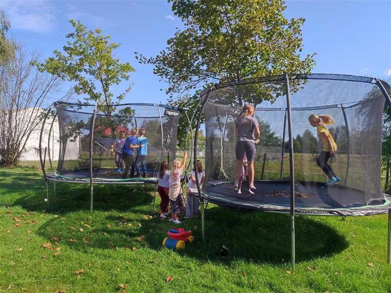 Dzieci z klas drugich skaczące na trampolinach w ogrodzie