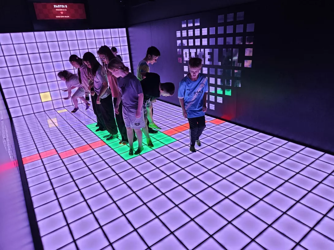 Uczennice i uczniowie skaczą na kolorowej podłodze