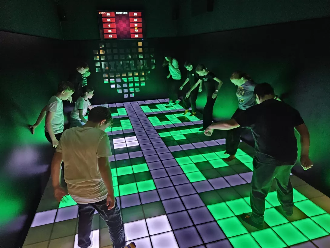 Uczennice i uczniowie skaczą na kolorowej podłodze