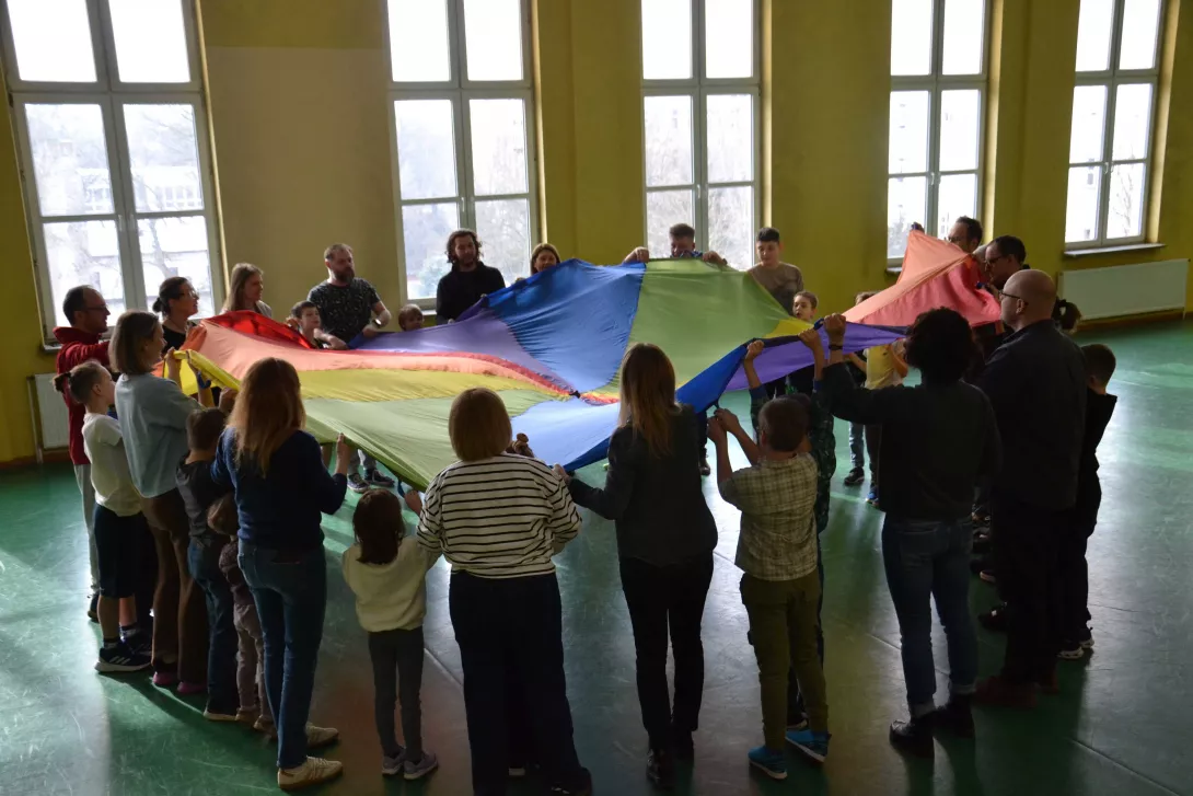 Uczestnicy spotkania w czasie zabawy chustą integracyjną.