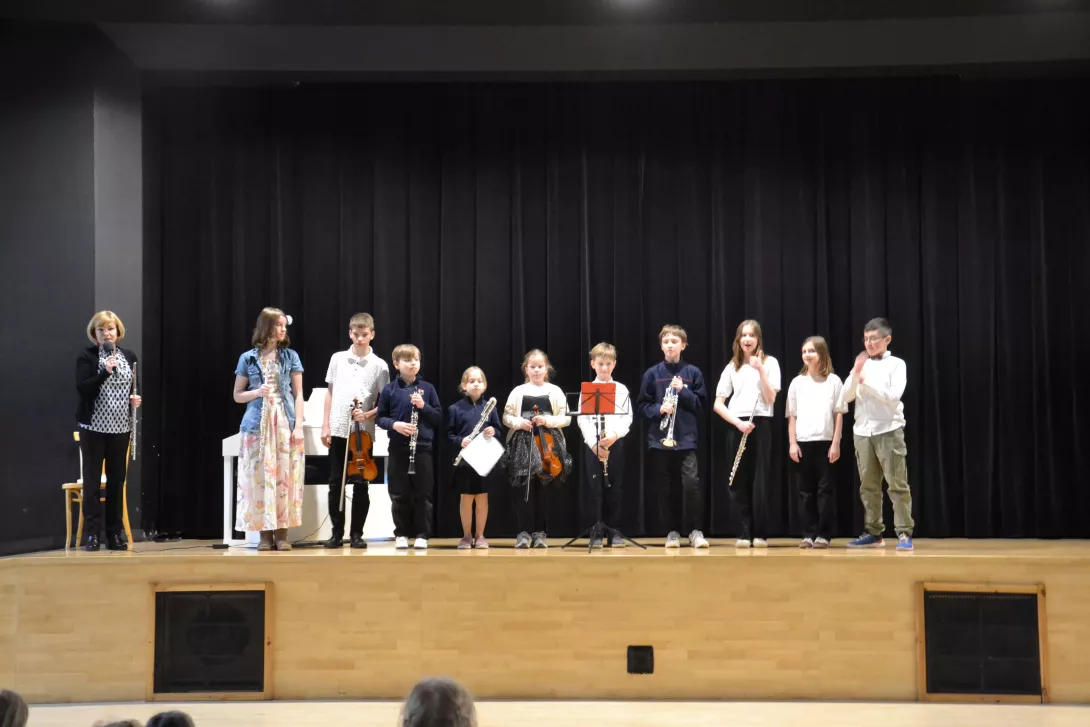 Zdjęcie grupowe artystów po występie dla uczniów klas 1-3 razem z prowadzącą nauczycielką.