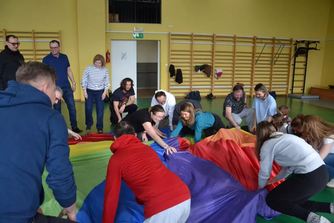 Uczestnicy spotkania w czasie zabawy chustą integracyjną.