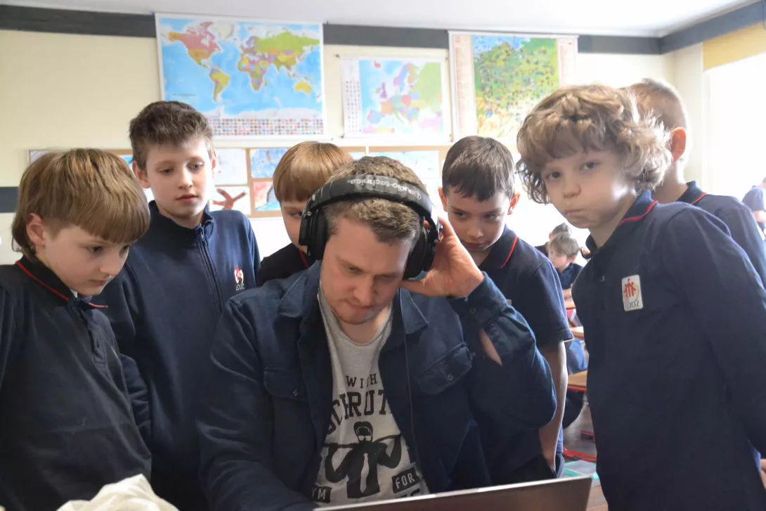 Uczniowie klasy 3b obserwują, jak Krzysztof Zimoch montuje słuchowisko "Ptasie radio". 