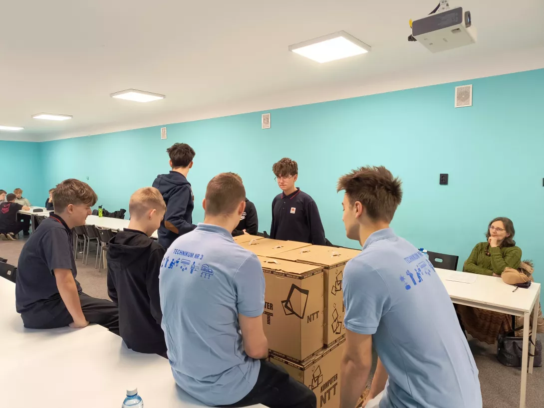 Układanie kartonów na palecie przez uczniów