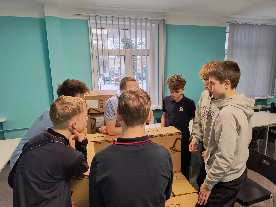 Układanie kartonów na palecie przez uczniów